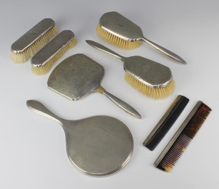 An engine turned silver backed hand mirror London 1918, 4 silver backed brushes, a mirror and 2 combs 