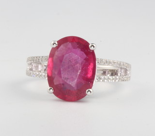 A 14ct white gold ruby and diamond ring, the centre oval treated stone approx. 5.38ct surrounded by brilliant cut diamonds approx. 0.3ct, size M 1/2
