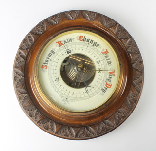 An aneroid barometer with porcelain dial contained in a carved walnut case 34cm 
