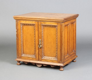 A Victorian light oak table top collectors cabinet, the interior fitted 4 long drawers with brass counter sunk handles, enclosed by a pair of panelled doors raised on bun feet 40cm h x 44cm w x 34cm d 