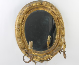 A 19th Century oval plate mirror in a decorative gilt frame with candle sconce to either side  57cm x 47cm 