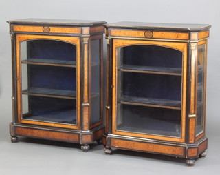 A pair of Victorian amboyna and ebonised pier cabinets fitted shelves enclosed by arched plate panelled doors and with gilt metal mounts, raised on bun feet 108cm x 80cm x 40cm 