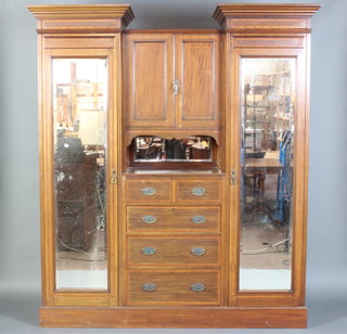 An Edwardian inlaid mahogany sentry box wardrobe, the centre section fitted a cupboard enclosed by panelled door above a recess, 2 short and 3 long drawers, flanked by a pair of hanging compartments enclosed by bevelled plate mirrored doors and raised on a platform base 213cm h x 188cm w x 56cm d 