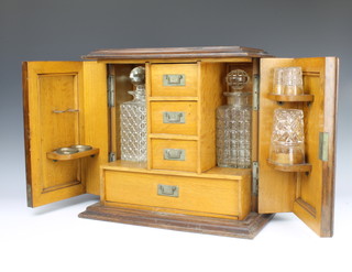 An Edwardian oak and silver plated mounted smokers cabinet fitted 3 long drawers flanked by a pair of recesses with 2 associated cut glass decanters, the base fitted a drawer complete with 3 glasses 37cm h x 39cm w x 23cm d  