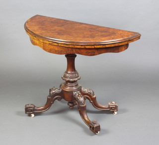 A Victorian figured walnut D shaped folding card table raised on a turned column and tripod base 73cm x 98cm x 47cm 
