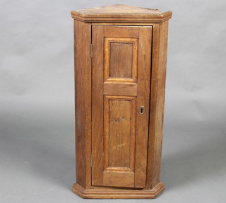 An 18th Century oak hanging corner cabinet with moulded cornice, fitted shelves enclosed by a panelled door 76cm x 38cm x 24cm 
