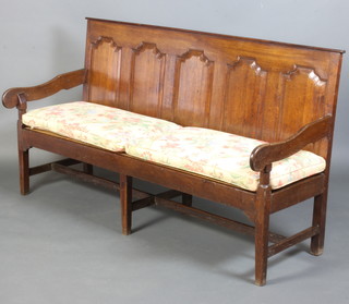 An 18th Century oak settle of panelled construction raised on square tapered supports 106cm h x 187cm w x 68cm d, complete with cushion seat  