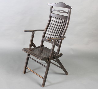 An Edwardian Art Nouveau style ebonised slatted wooden campaign armchair 