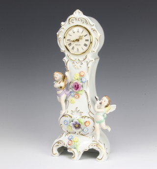 A 20th Century Continental porcelain timepiece encrusted with flowers and musical playing cherubs, having a quartz Mercedes movement, raised on rococo feet 33cm 