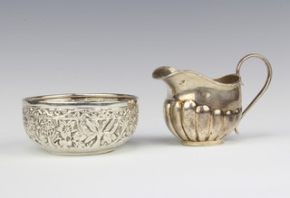 An Edwardian silver demi-fluted cream jug Birmingham 1901 and an Indian repousse silver bowl, 133 grams 