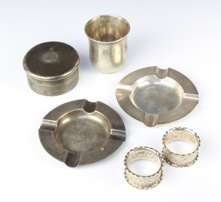 A circular silver engine turned box London 1920, cup, 2 napkin rings and 2 ashtrays, 323 grams 