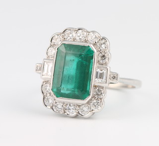 An 18ct white gold emerald and diamond cluster ring, the centre cut stone approx. 3ct surrounded by brilliant and baguette cut diamonds size O 