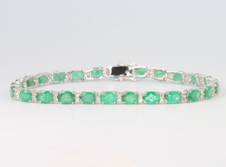 An 18ct white gold emerald and diamond line bracelet, the diamonds approx. 0.65ct, emeralds approx. 8.31ct