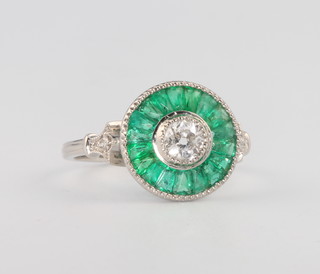 A platinum, emerald and diamond target ring, the centre mine cut stone approx. 0.5ct size N 1/2 13mm