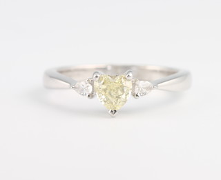 An 18ct white gold heart shaped diamond ring, the coloured centre stone approx. 0.5ct flanked by diamonds 