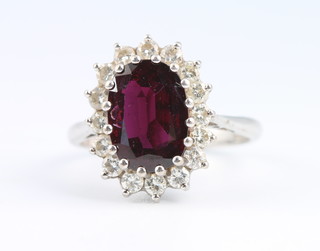 An 18ct yellow gold Edwardian style oval ruby and diamond cluster ring, the centre stone approx. 3ct, the brilliant cut diamonds approx. 1ct, size N 1/2