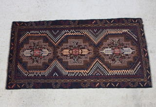 A black and brown ground Baluchi rug with 3 stylised medallions to the centre 192cm x 160cm 