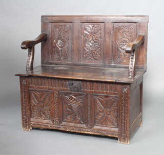 A carved oak settle formed from a coffer with raised back and hinged lid 100cm h x 104cm w x 51cm d 