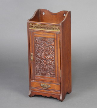 An Edwardian patented carved walnut smokers cabinet, the raised back with pierced gallery above cupboard, fitted a drawer and pipe rack, enclosed by a carved panelled door 51cm h x 21cm w x 17cm d, the top bears RD no. 215604 