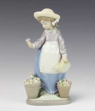 A Lladro figure of a young girl with a butterfly on her hand beside pots of flowers no.5543 19cm, boxed 
