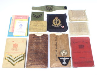 Two eye shield anti-gas shields, 2 first aid field dressings, a small collection of cloth insignia, one volume "Drill (All Arms 1965)", a Regular Army certificate of service relating to Unwin Edward Jones Stanley show served from 1919 to 1931 and other ephemera  