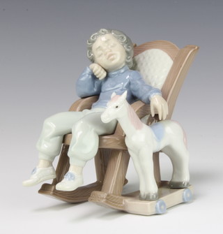 A Lladro figure of a boy sleeping in a rocking chair with a pull along horse beside him no.5846 14cm 