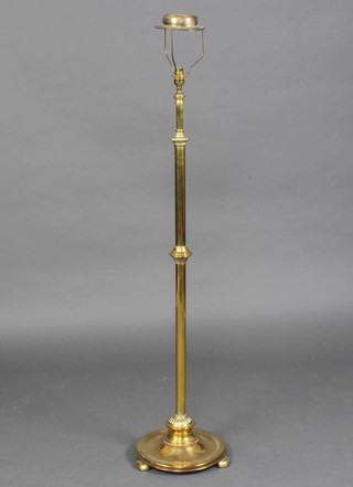 A brass adjustable standard lamp raised on a circular base 