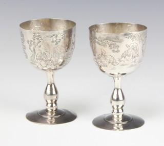 A pair of Chinese silver egg cups with chased landscape decoration 8.5cm, 110 grams