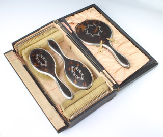 A silver and tortoiseshell dressing table set comprising hand mirror, 2 hair brushes and 2 clothes brushes, Birmingham 1917, cased