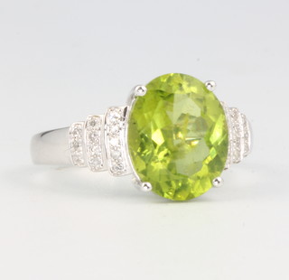 A 14ct white gold peridot and diamond ring, the centre oval stone approx. 3.56ct flanked by 12 brilliant cut diamonds approx 0.25ct, size M 