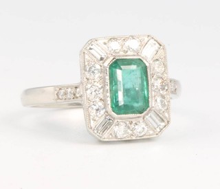 A white gold Art Deco style emerald and diamond ring, the rectangular cut centre stone approx 0.75ct surrounded by baguette and brilliant cut diamonds size O 1/2