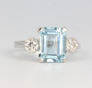 An 18ct white gold emerald cut aquamarine and diamond ring, the centre stone approx. 3cts flanked by 2 brilliant cut diamonds approx. 0.5ct, size N 