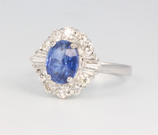 An 18ct white gold oval sapphire and diamond cluster ring, the centre stone 2.09ct, the tapered baguette diamonds 0.18ct and the brilliant cut diamonds 0.66ct, size N 