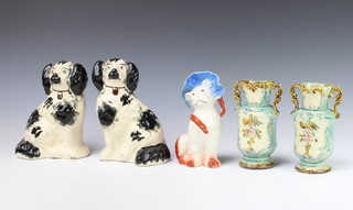 A pair of Victorian Staffordshire black and white spaniels 20cm, a German figure of a dog wearing a bonnet 15cm and a pair of Majolica 2 handled vases 15cm 
