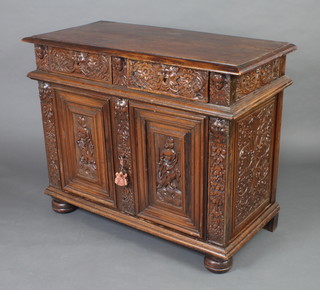 An 18th Century carved oak cabinet fitted 2 long drawers decorated the Green Man above a pair of cupboards enclosed by panelled doors decorated mythical figures, raised on bun feet, heavily carved throughout 90cm h x 111cm w x 54cm d 