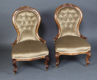 A pair of Victorian carved walnut show frame nursing chairs, the backs upholstered in buttoned material the seats of serpentine outline, raised on cabriole supports 