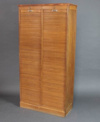 A mid 20th Century light oak office filing cabinet fitted shelves and enclosed by a tambour shutter 181cm h x 90cm w x 40cm d 
 