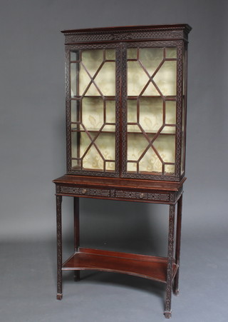An Edwardian Chippendale style mahogany display cabinet on stand with blind fretwork decoration throughout, the upper section fitted adjustable shelves enclosed by astragal glazed panelled doors, the base fitted 2 short drawers above an undertier, raised on square tapered supports 153cm h x 73cm w x 34cm d 