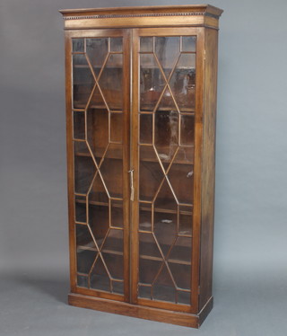 An Edwardian mahogany bookcase/display cabinet with moulded and dentil cornice, fitted shelves enclosed by astragal glazed panelled doors, raised on a platform base 193cm h x 90cm w x 36cm d 
