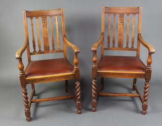 A pair of 1930's Art Deco oak stick and rail back carver chairs with upholstered drop in seats raised on spiral turned supports 