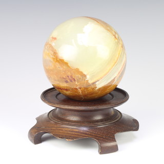 A circular carved onyx sphere 9cm raised on a hardwood base 