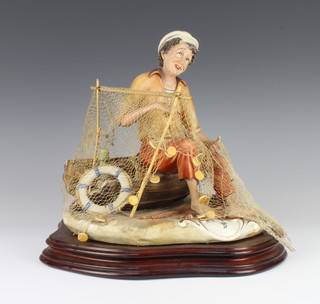 A Capodimonte figure of a fisherman sitting on a boat mending his nets 25cm  