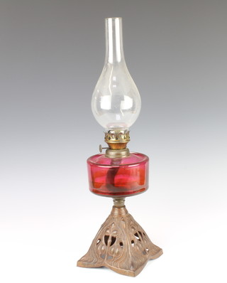 A Victorian glass oil lamp with ruby glass reservoir, raised on a pierced iron base 55cm x 15cm 