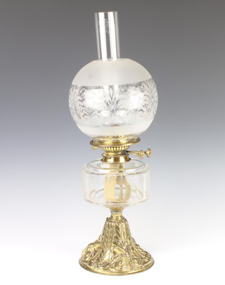 A Victorian clear faceted glass oil lamp reservoir (2 faults to the glass) raised on an embossed gilt metal base decorated a ram together with an associated etched glass shade