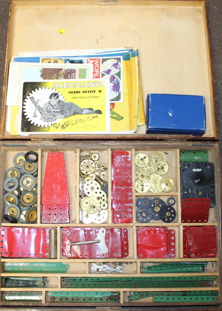 A Meccano clockwork motor no.1 boxed and with key together with a shallow wooden box containing a collection of various red and green Meccano 