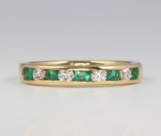 An 18ct yellow gold channel set emerald and diamond ring size M 