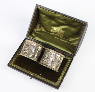 A pair of Edwardian oval repousse silver napkin rings decorated with a nymph beneath a tree with birds 70 grams, cased