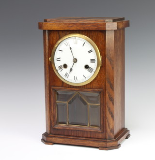 An Edwardian 8 day striking mantel clock with enamelled dial and Roman numerals contained in an oak case complete with pendulum 