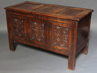 A 17th/18th Century carved oak coffer of panelled construction with hinged lid and iron lock, the front panel carved tulips 71cm h x 122cm w x 56cm d 