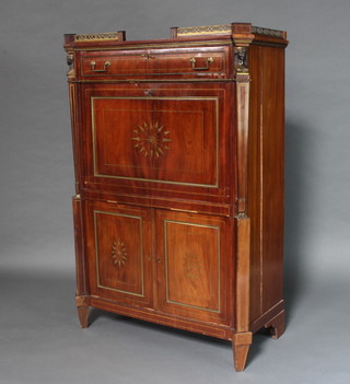 A 19th Century French Empire style mahogany and gilt mounted escritoire the upper section with brass 3/4 gallery, fitted a drawer, the inlaid fall front decorated arrows reveals a well fitted interior with cupboard and 6 short drawers above a double cupboard, raised on square tapered supports 150cm h x 100cm w x 48cm d 
